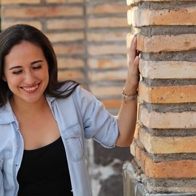 A smiling client standing outdoors beside a brick column