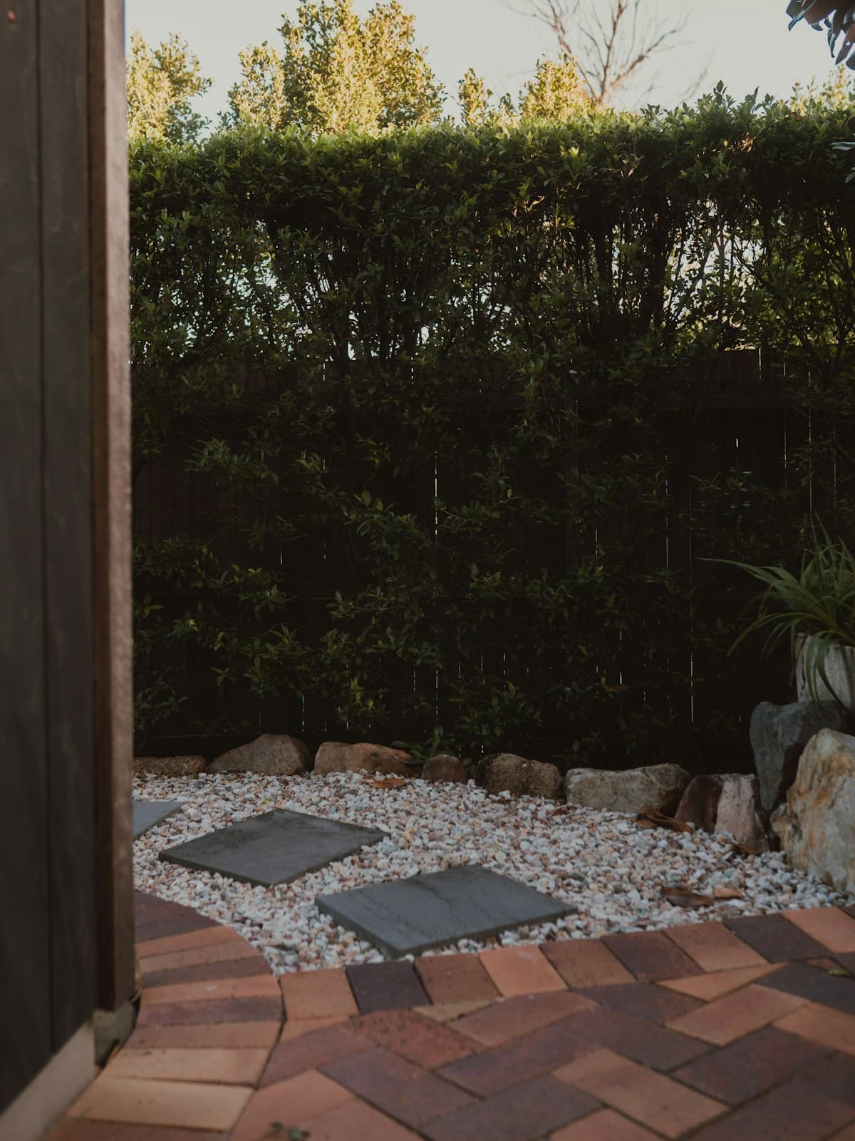 A garden of brick paths, gravel and clipped green hedging