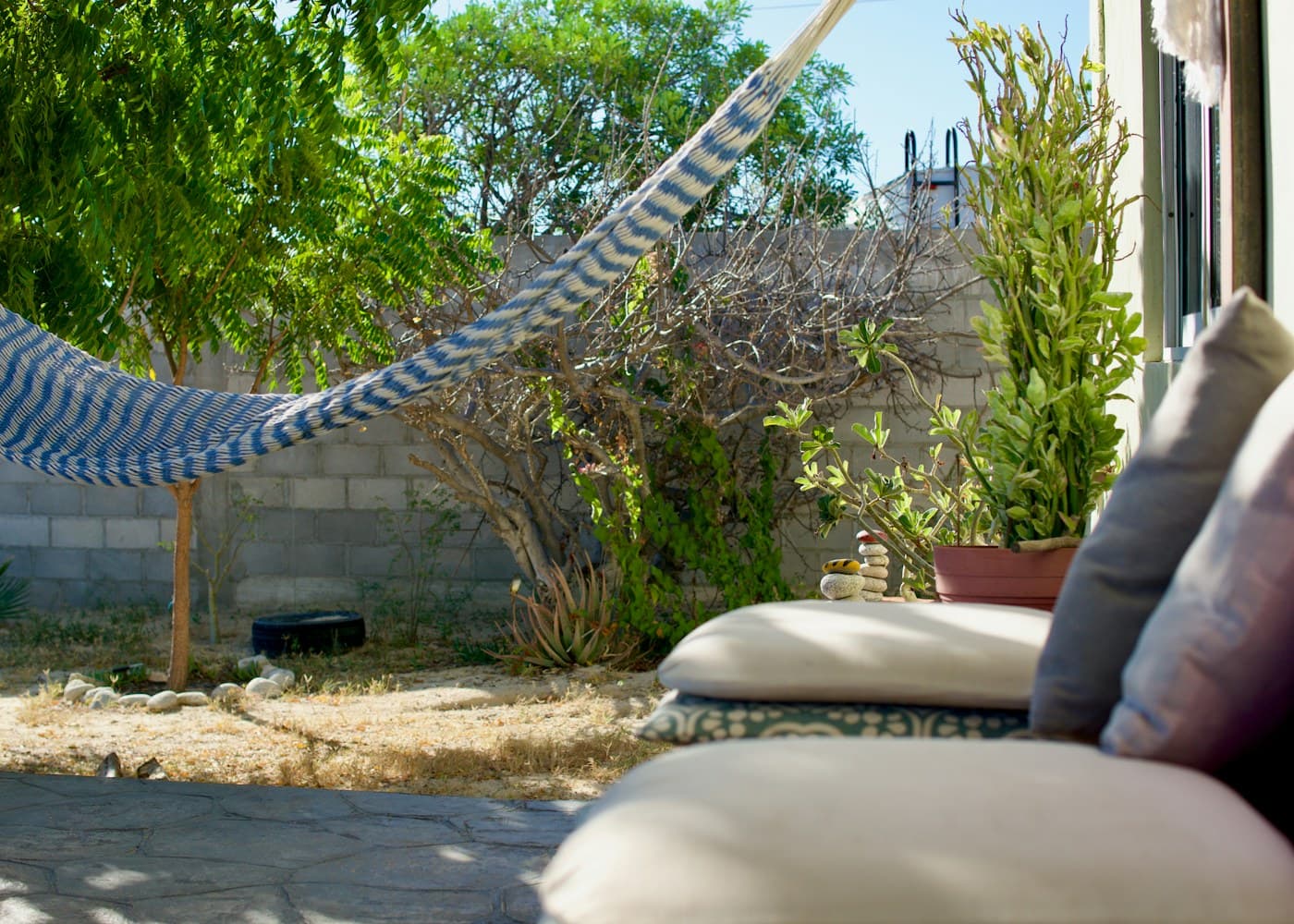 A hammock strung in a sunny backyard beside outdoor seating