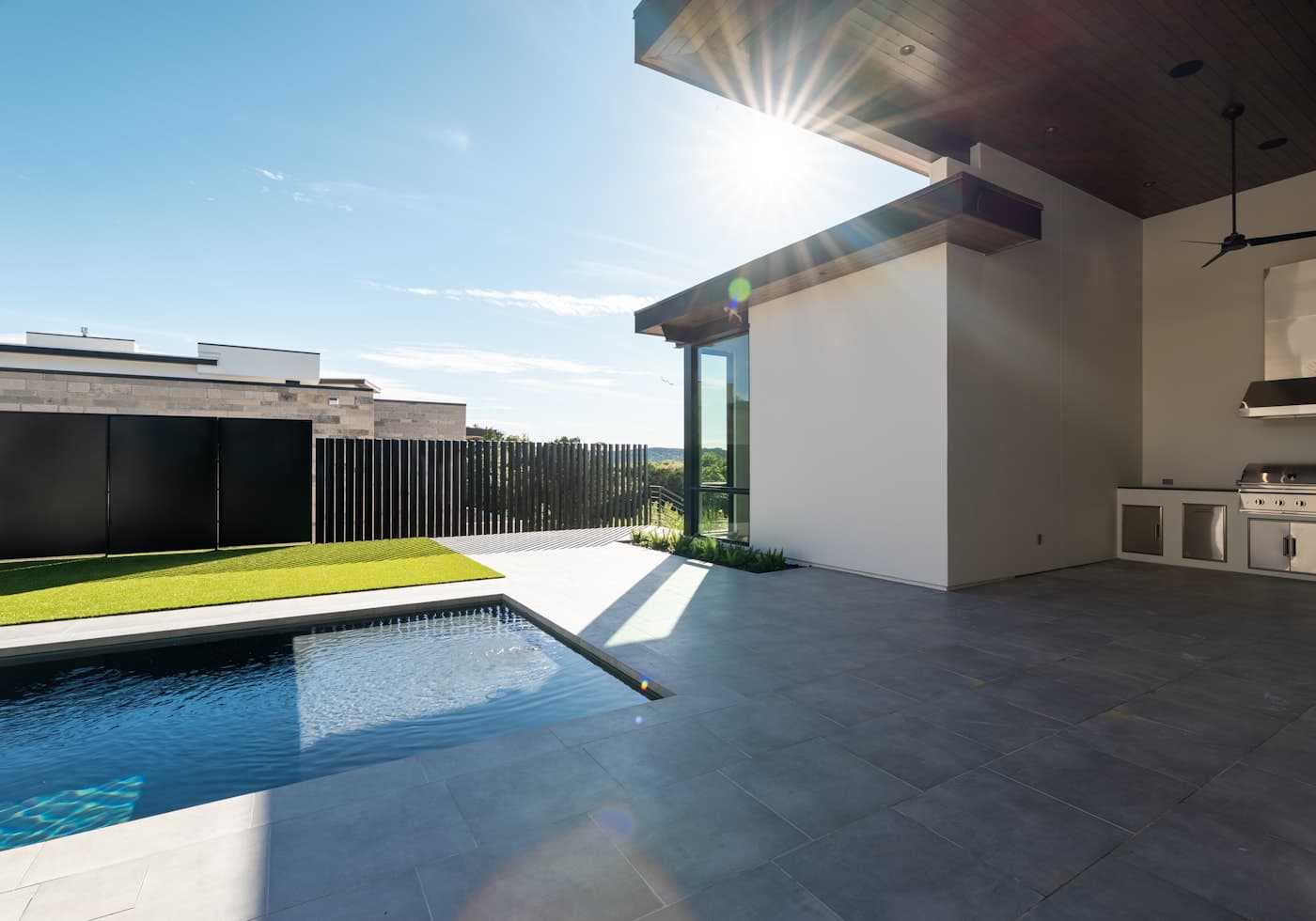 A modern patio with a swimming pool and a built-in outdoor kitchen
