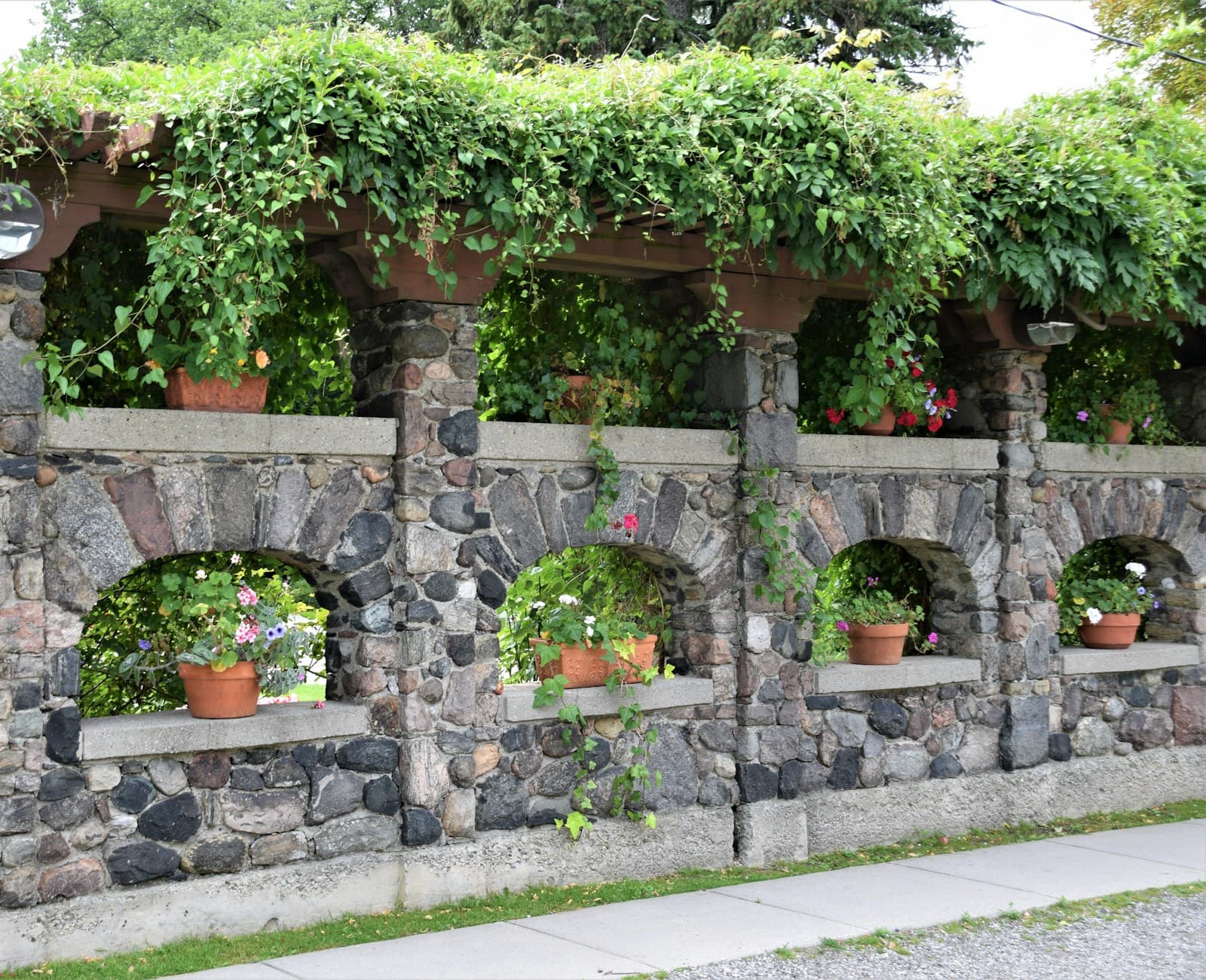 A stone garden wall planted with potted specimens