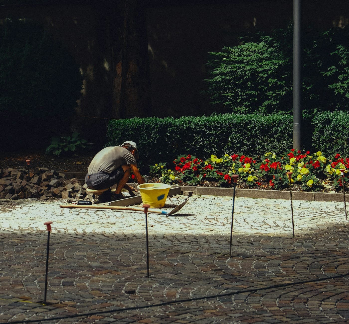 A gardener setting stones into a planted flower bed
