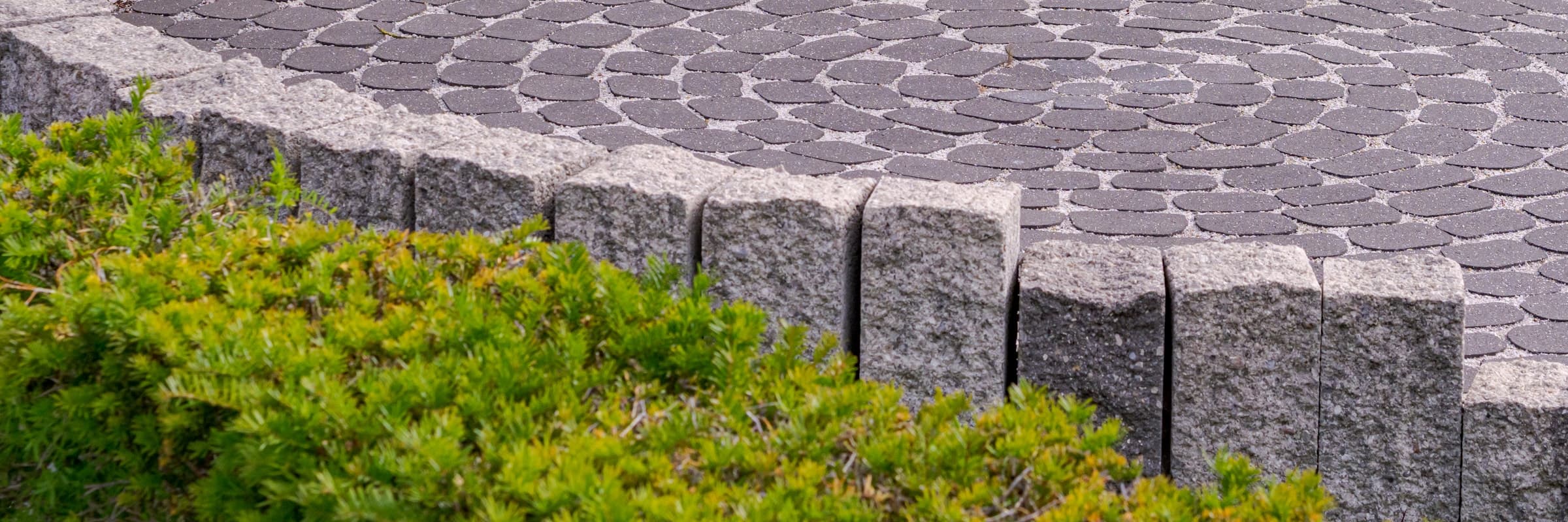 A circular paved patio edged by a low stone wall and clipped shrubs