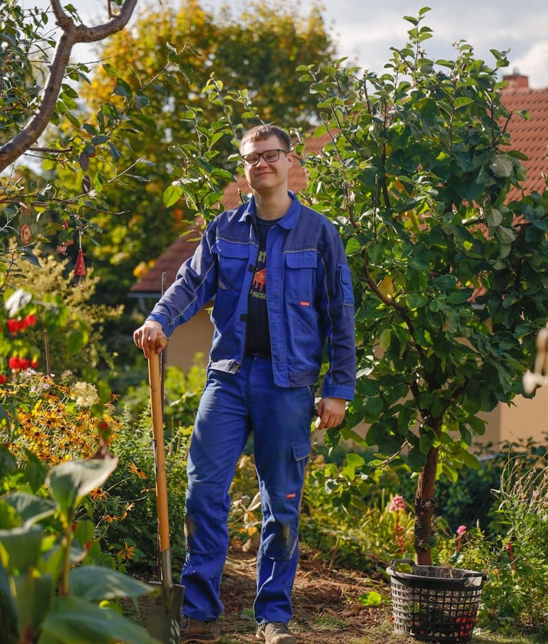 A member of the Verdora crew in work clothes, holding a spade in a garden